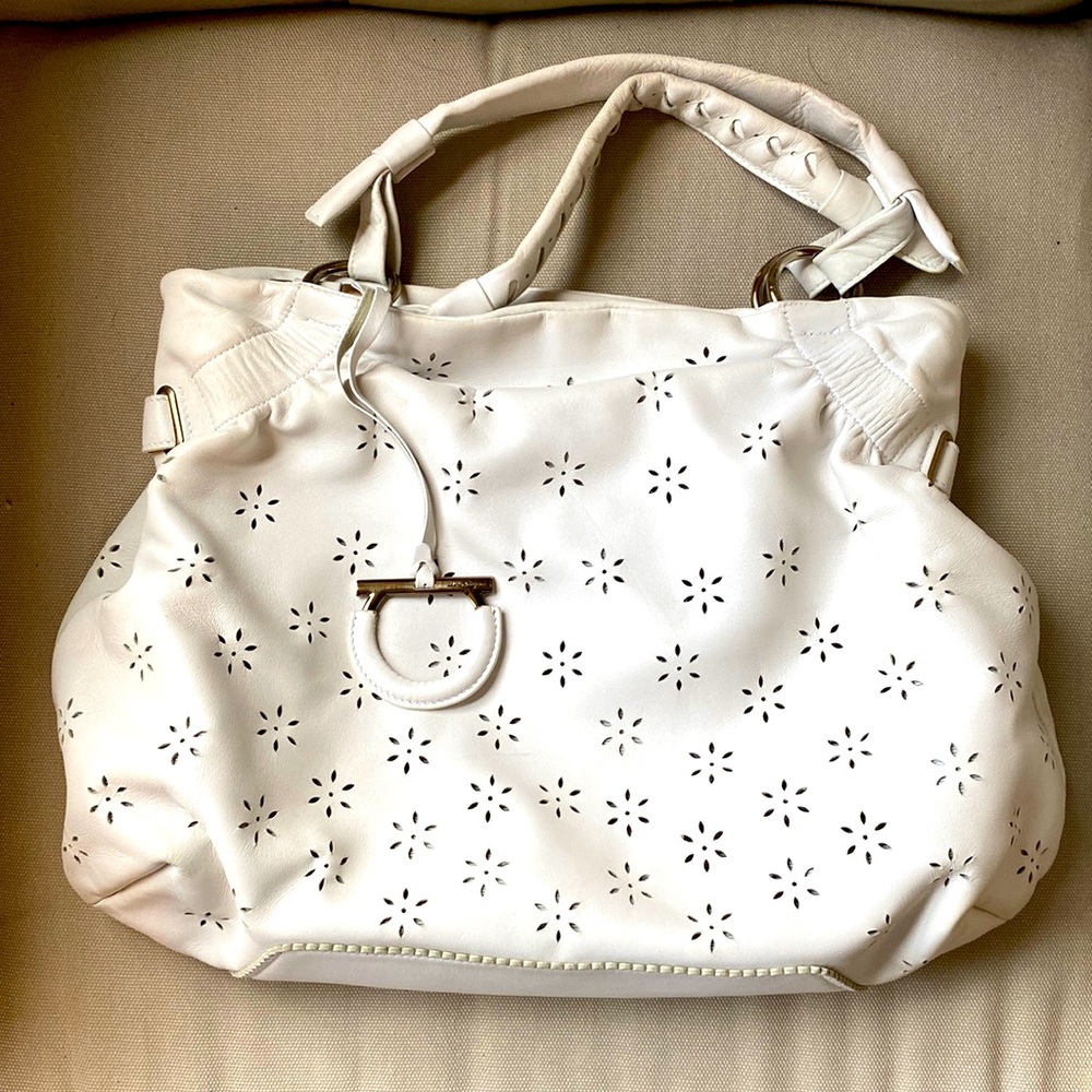 Top handle white leather Ferragamo bag with laser floral cutout details.